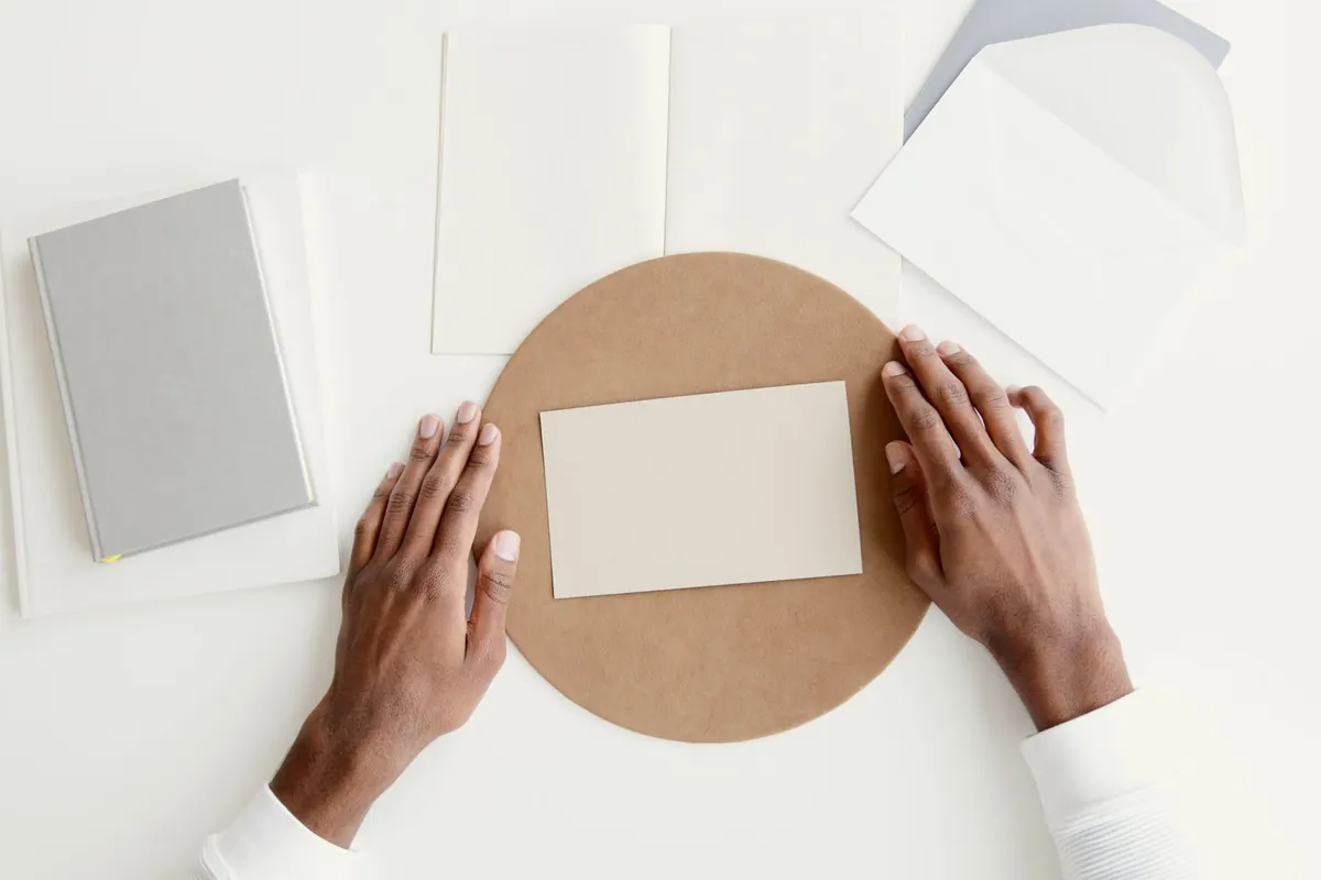 Hands arranging items on a clean white surface for a flat lay shot