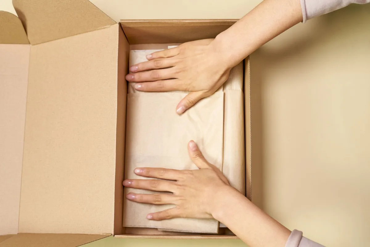 Hands packing a product into a cardboard box