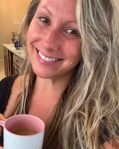 Trish Leto smiling over a pink coffee mug in her kitchen